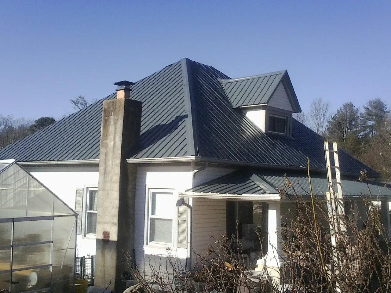 Dark blue standing seam metal roof on a white farmhouse with dormer — Slate & Tile Roof Repair by Roofing Brothers in Dewitt