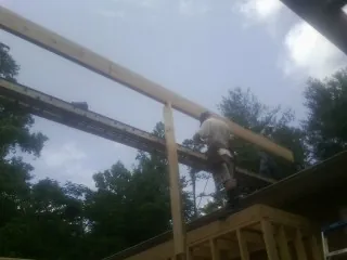 Carpenter setting a ridge beam over a new addition frame — Ice Dam Removal by Roofing Brothers in Dewitt