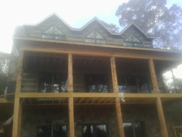 Dormers and porch framing on a large log home under construction — Roof Coating work by our crew in Dewitt