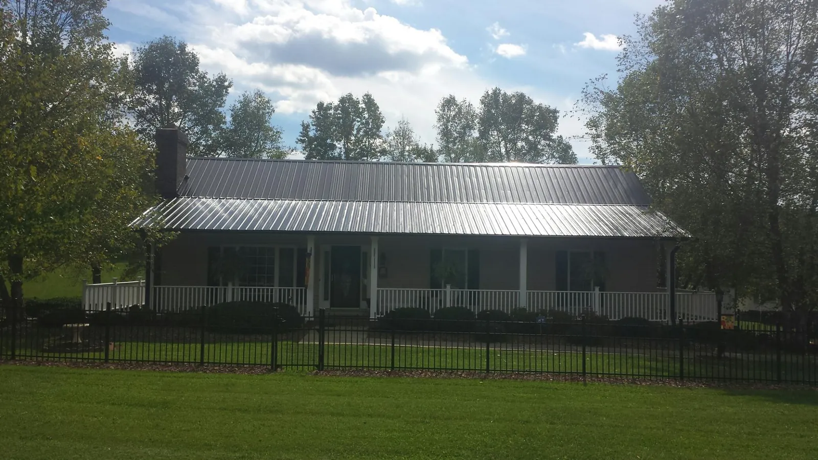 Gray metal roof on a brick ranch with a full width front porch — Gutter Guard Installation work by our crew in Dewitt